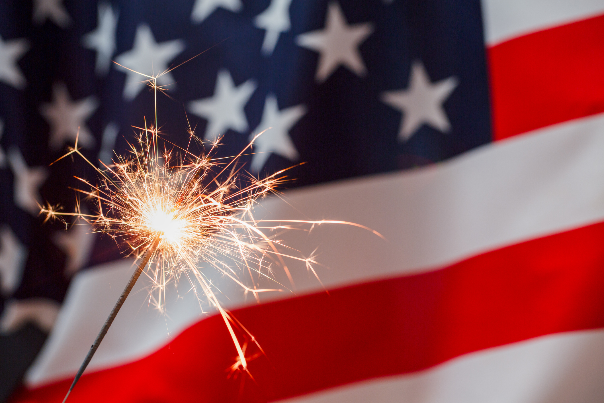 Sparkles with lights and American flag on the background. July forth celebration.